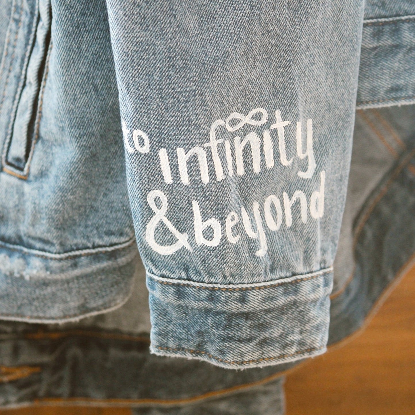 Hand-Painted Bridal Denim Jacket featuring delicate flowers, personalized with initials and love quote. Unique and chic fashion for a memorable wedding day. #BridalStyle #WeddingFashion