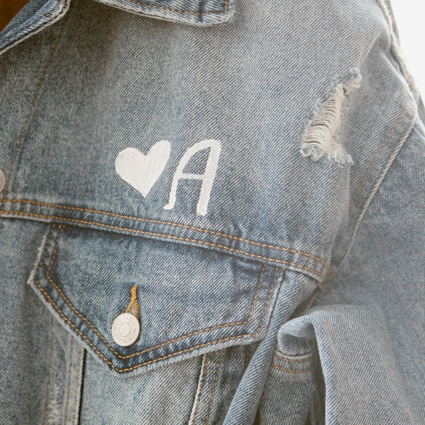 Hand-Painted Bridal Denim Jacket featuring delicate flowers, personalized with initials and love quote. Unique and chic fashion for a memorable wedding day. #BridalStyle #WeddingFashion